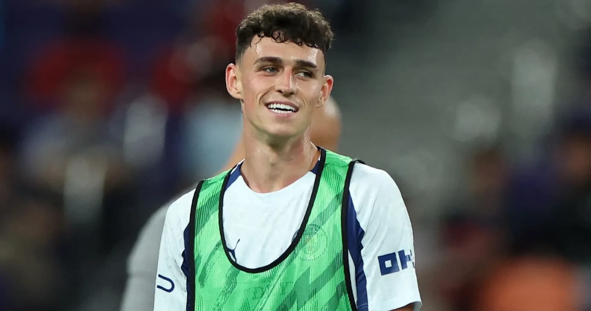 Player in training vest smiling on the pitch