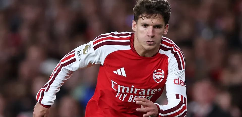 Futbolçu Arsenal formasında topa doğru irəliləyir