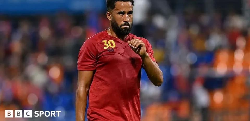 Futbolçu qırmızı formada meydanda yürüyür