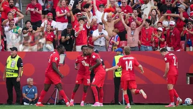 Players celebrating goal with enthusiastic crowd in background