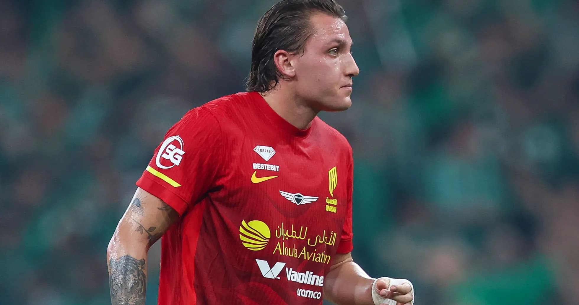 Futbolçu qırmızı forma ilə meydanda yürüyür