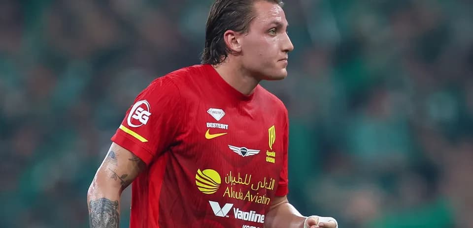 Futbolçu qırmızı forma ilə meydanda yürüyür