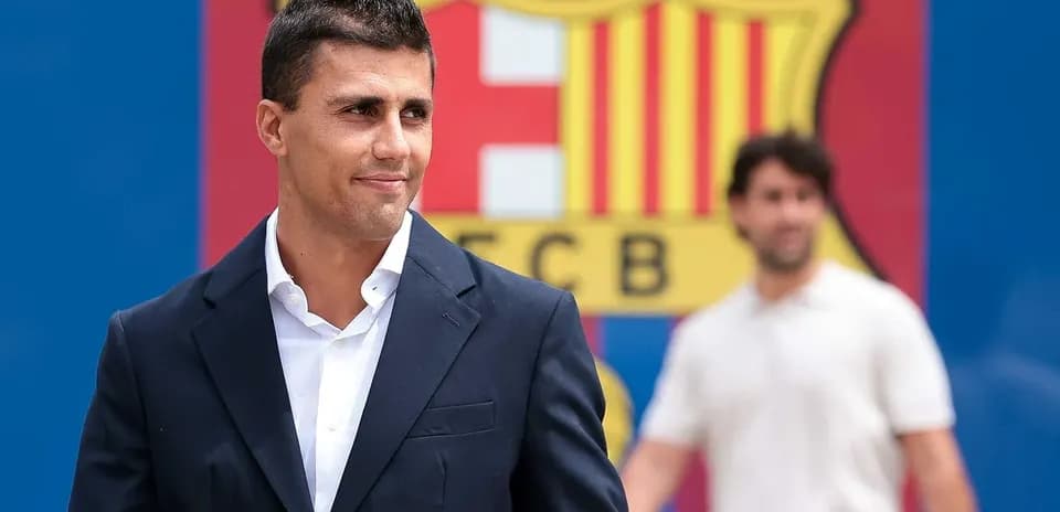 Person in suit near FC Barcelona logo backdrop