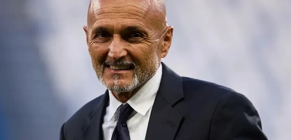 An older man in a suit smiling at the camera