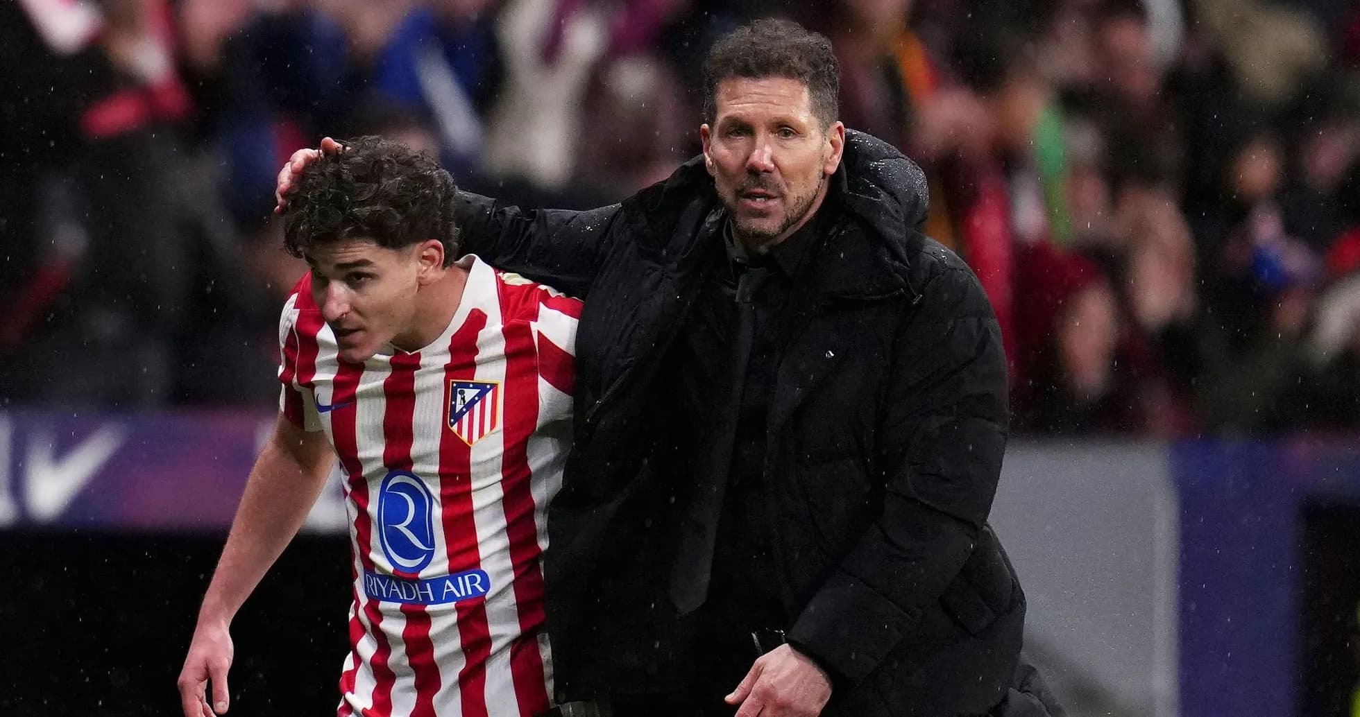 Atletico Madrid coach assisting player off the field