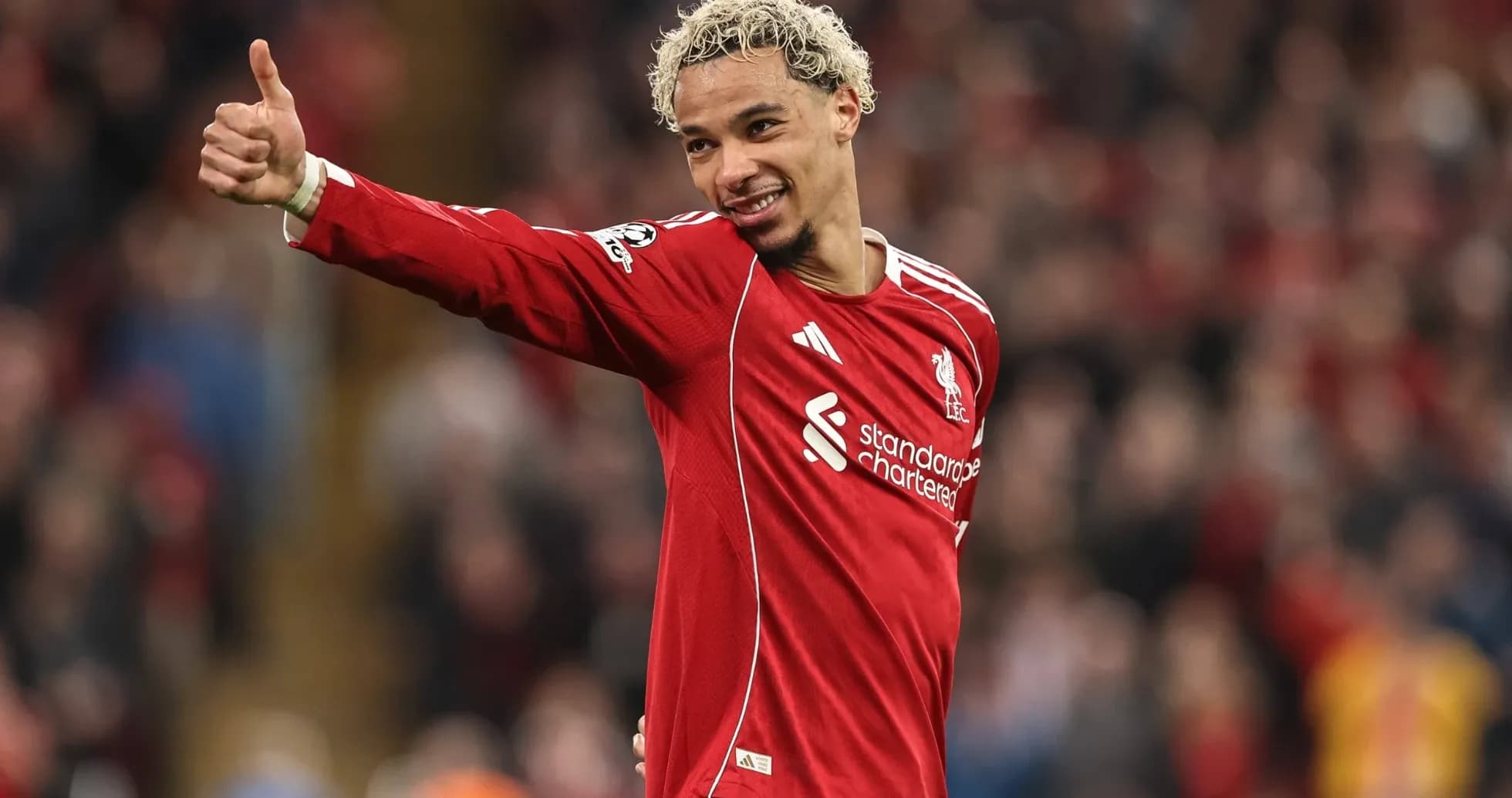 Futbolçu Liverpool formasında əlini yuxarı qaldırır
