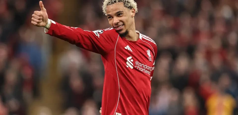 Futbolçu Liverpool formasında əlini yuxarı qaldırır