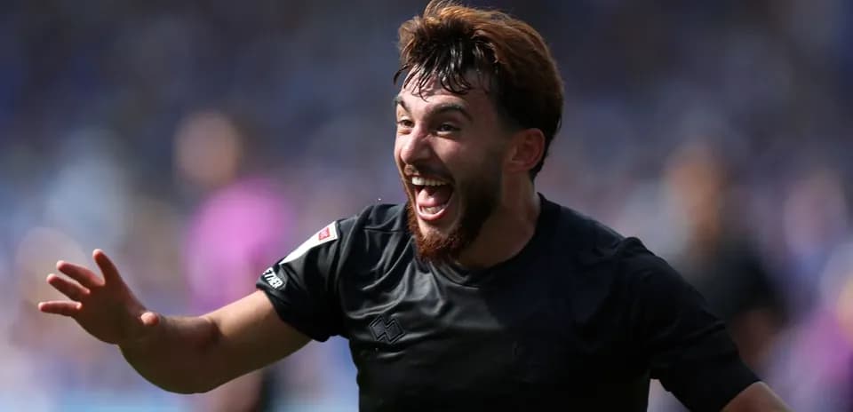 Futbolçu sevinclə qollarını açmış şəkildədir