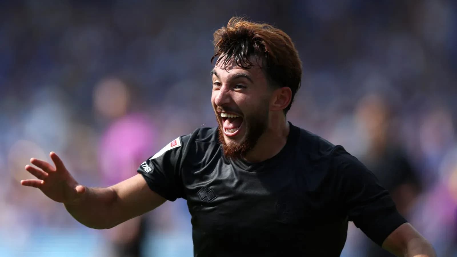 Futbolçu sevinclə qollarını açmış şəkildədir
