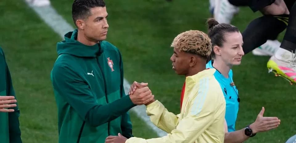 İki futbolçu əl sıxışır, hakem arxada durur