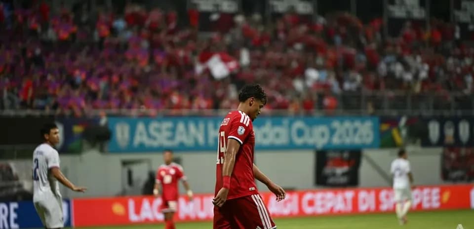 Player walking off field during match with fans in background