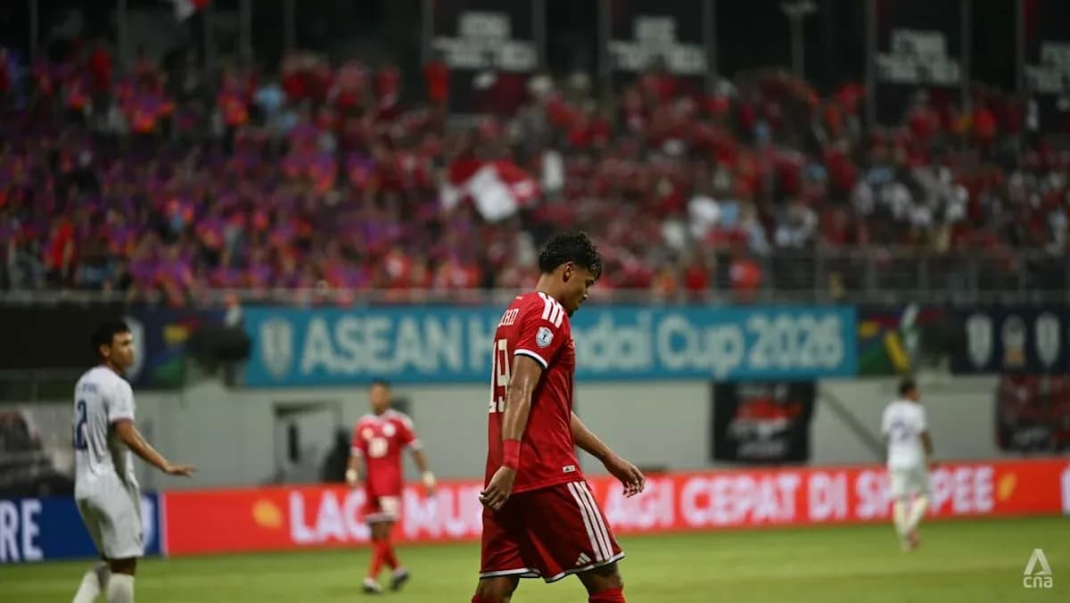 Player walking off field during match with fans in background