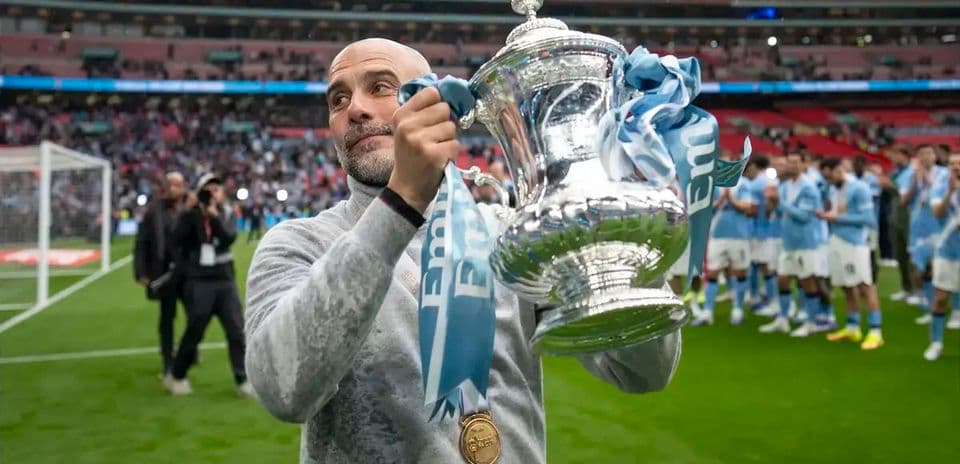 Men's football coach holding trophy at Wembley Stadium