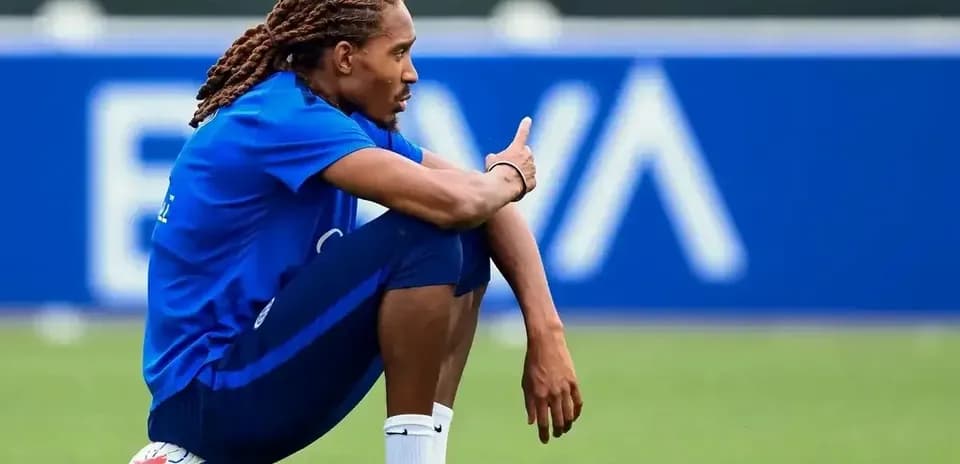 Futbolçu topun yanında oturaraq barmağı ilə işarə edir