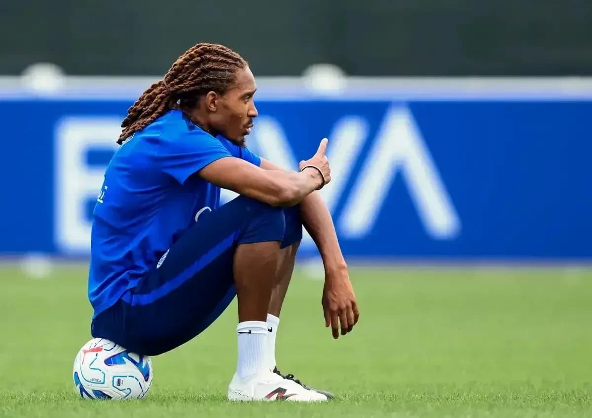 Futbolçu topun yanında oturaraq barmağı ilə işarə edir