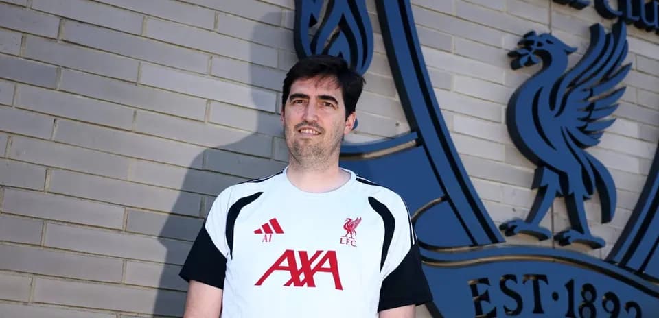 Person standing in front of Liverpool FC logo