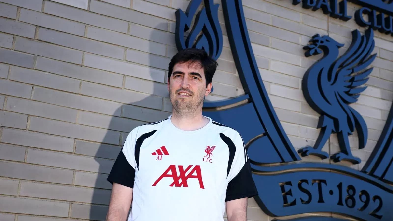 Person standing in front of Liverpool FC logo