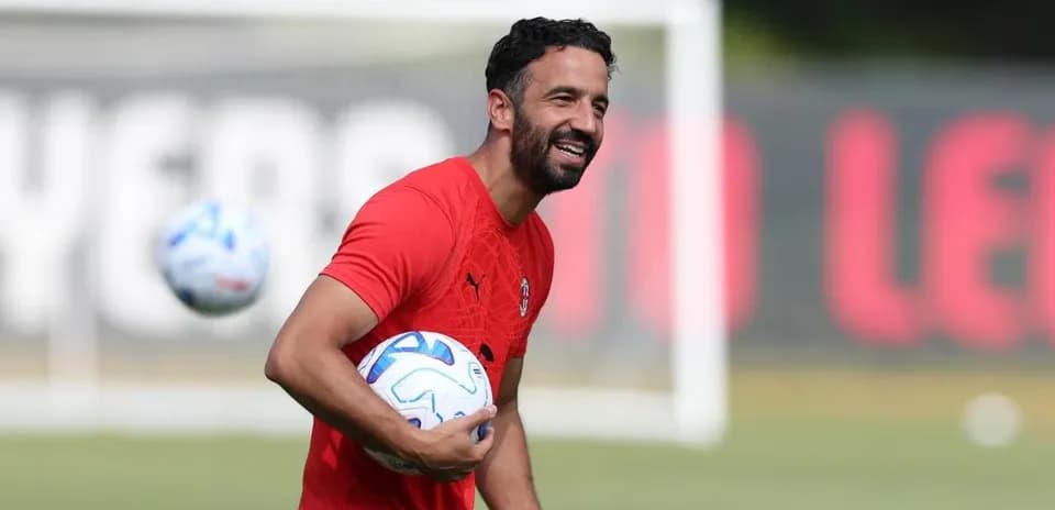Futbolçu məşq zamanı topu tutaraq gülür
