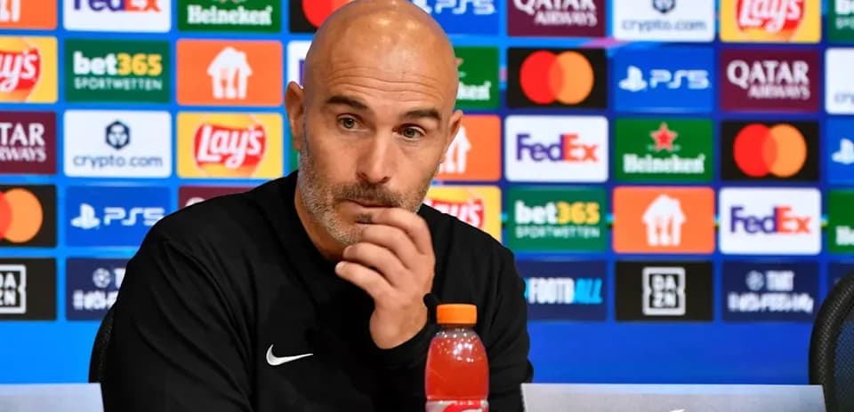 Men's football manager at press conference podium