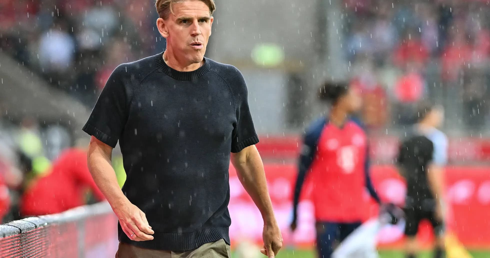 Coach walking on the sideline during rainy match