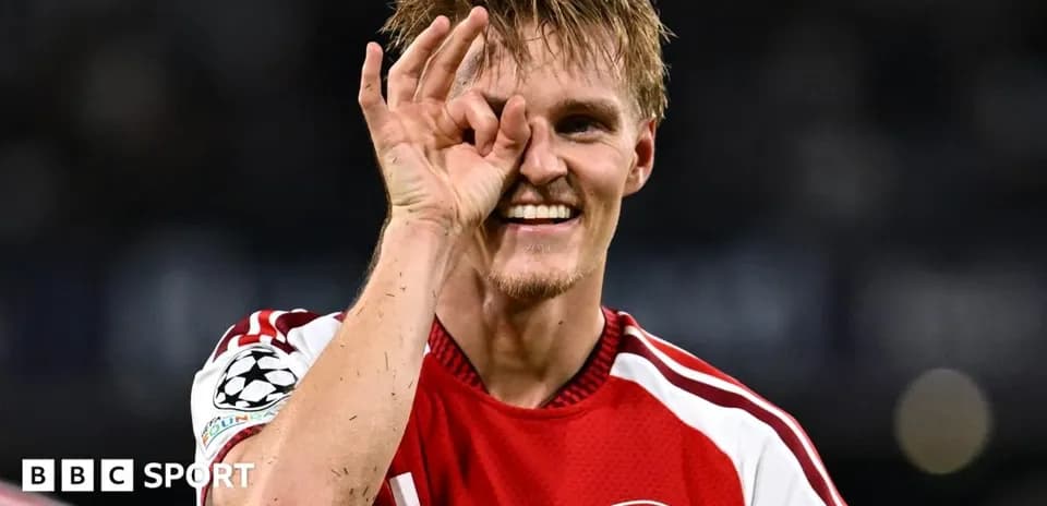 Futbolçu Arsenal formasında gülərək əl işarəsi edir