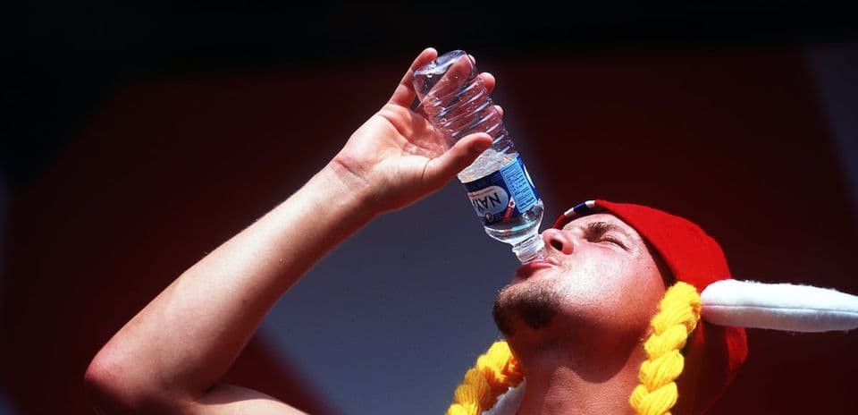 Person in a red hat drinking water from bottle