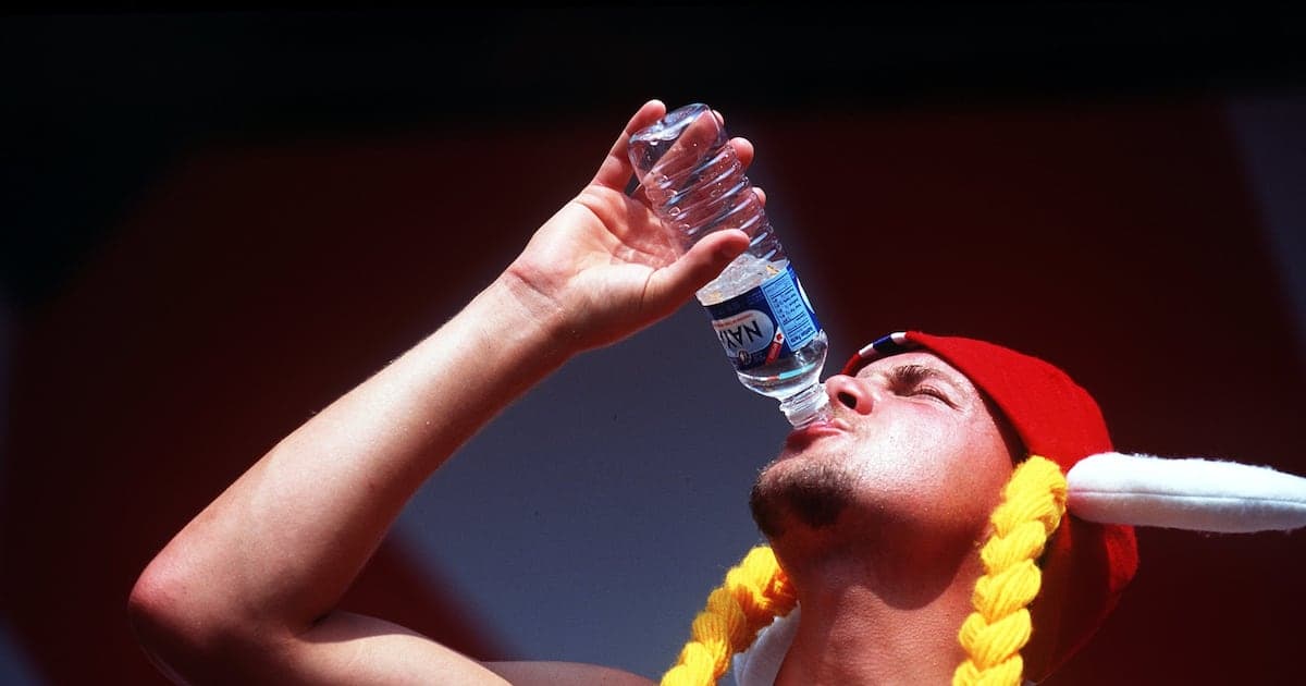 Person in a red hat drinking water from bottle