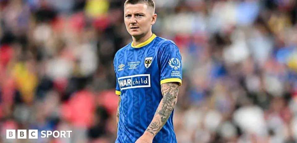 Futbolçu mavi forma ilə meydanda durur