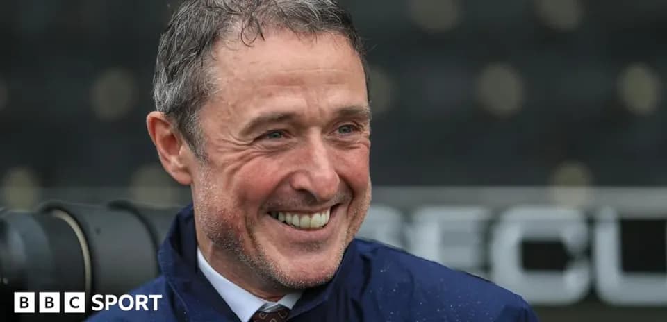 Coach smiling during press conference at stadium