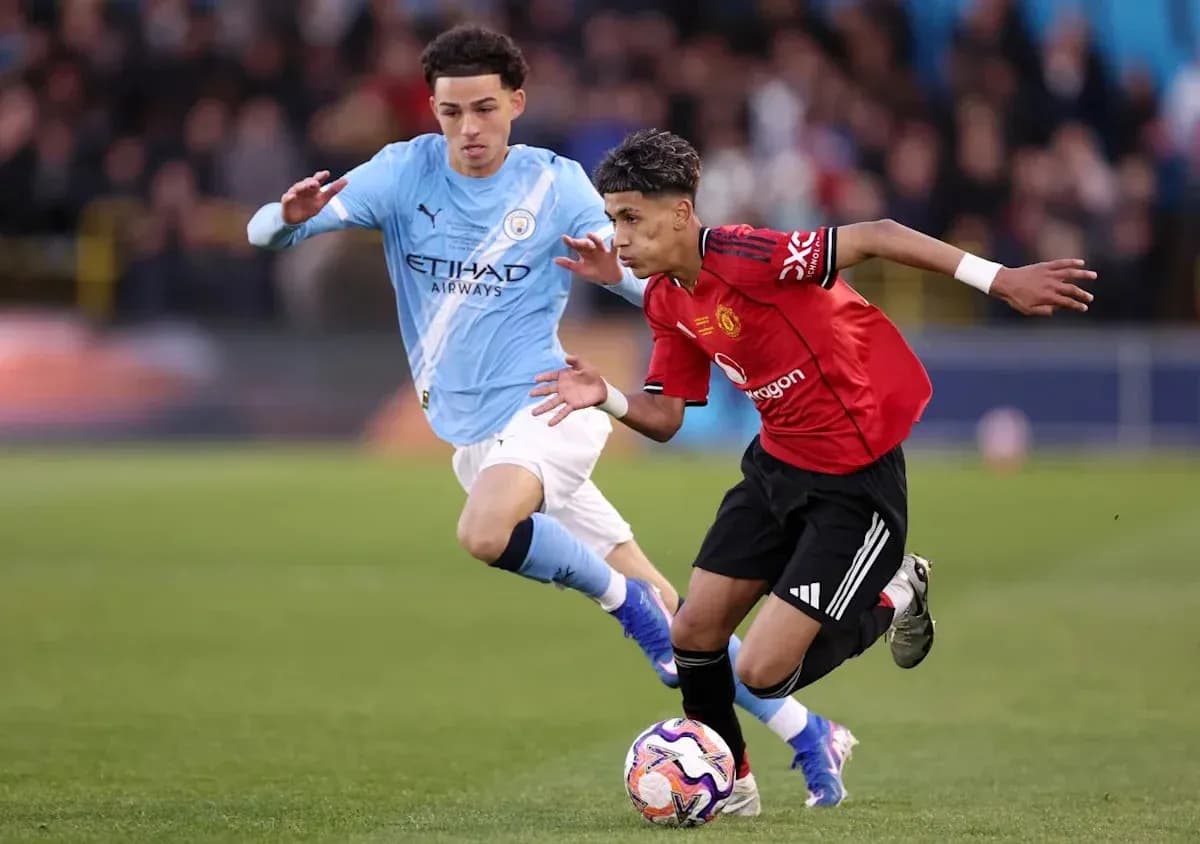 Manchester United player dribbling past Manchester City opponent