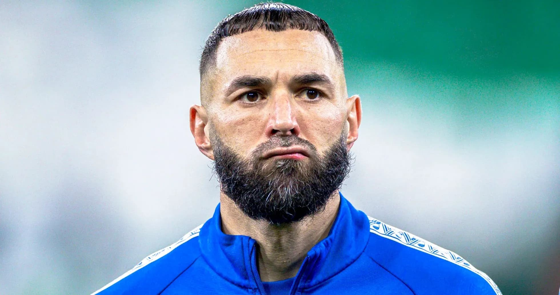 Futbolçu mavi forma geyinib, üz ifadəsi ciddi