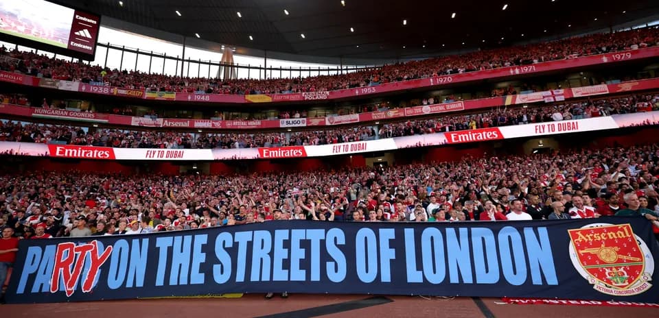 Arsenal fans holding banner in stadium stands