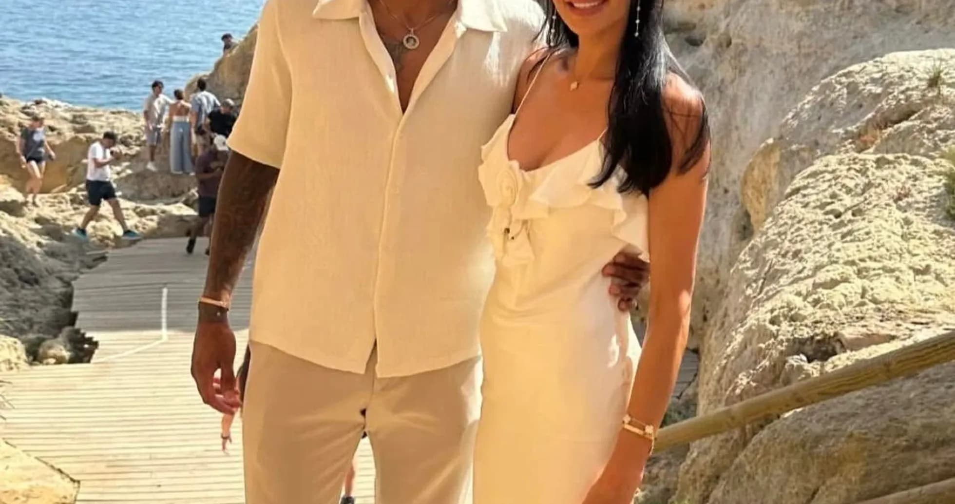 Pair posing together near rocky coastline