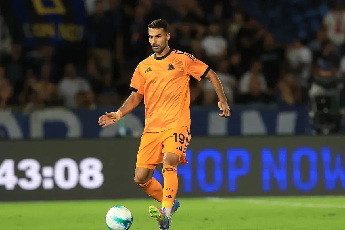 Player in orange kit dribbling ball on field