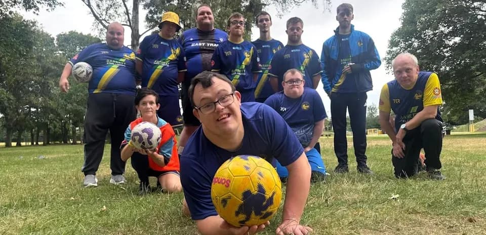 Soccer team posing with balls in park