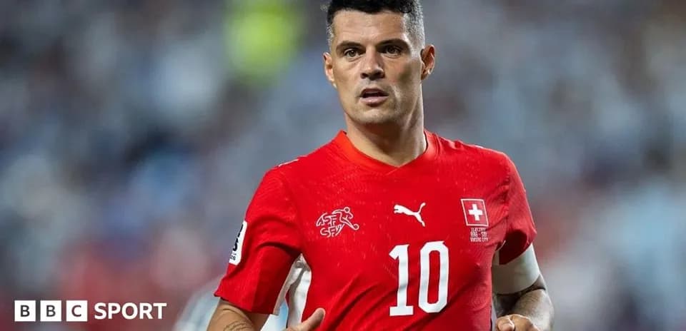 Futbolçu qırmızı forma ilə meydanda yürüyür