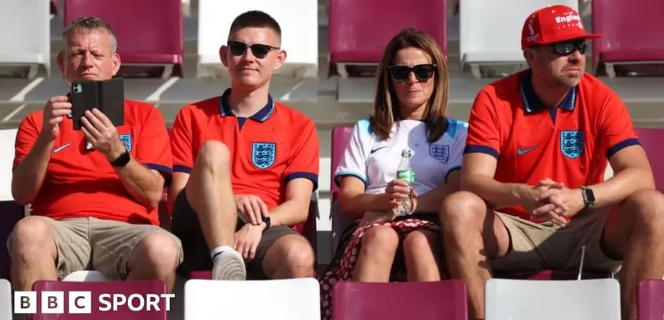 Fans wearing England jerseys in stadium seats