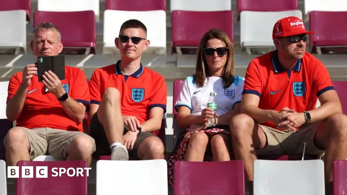 Fans wearing England jerseys in stadium seats
