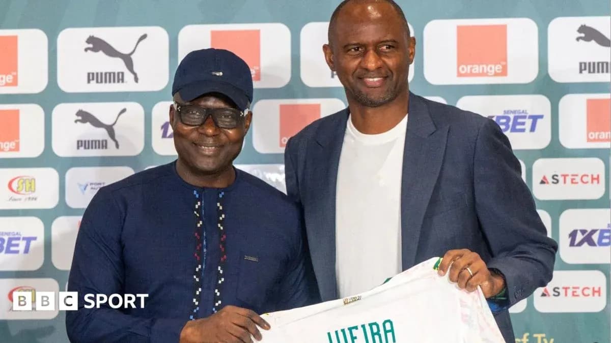 Two men holding a football jersey at press conference