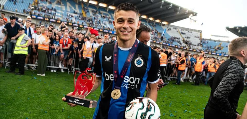 Player celebrating with trophy and fans in stadium