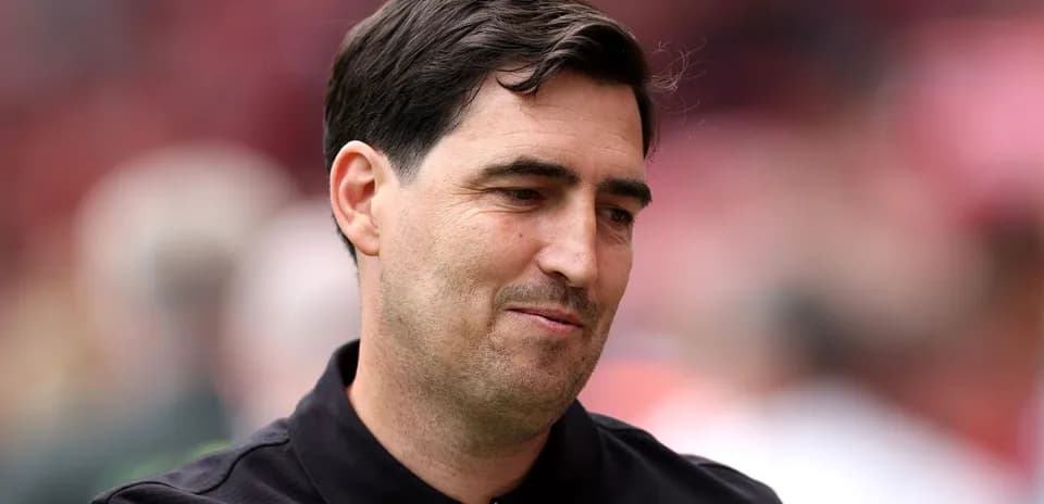 A man in a black shirt smiling slightly