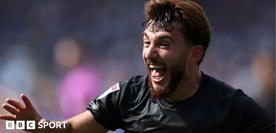 Futbolçu sevinclə qollarını qaldırır