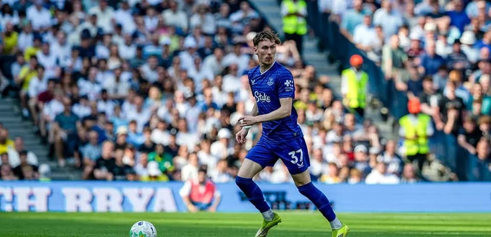 Futbolçu topu idarə edir, arxa planda azarkeşlər