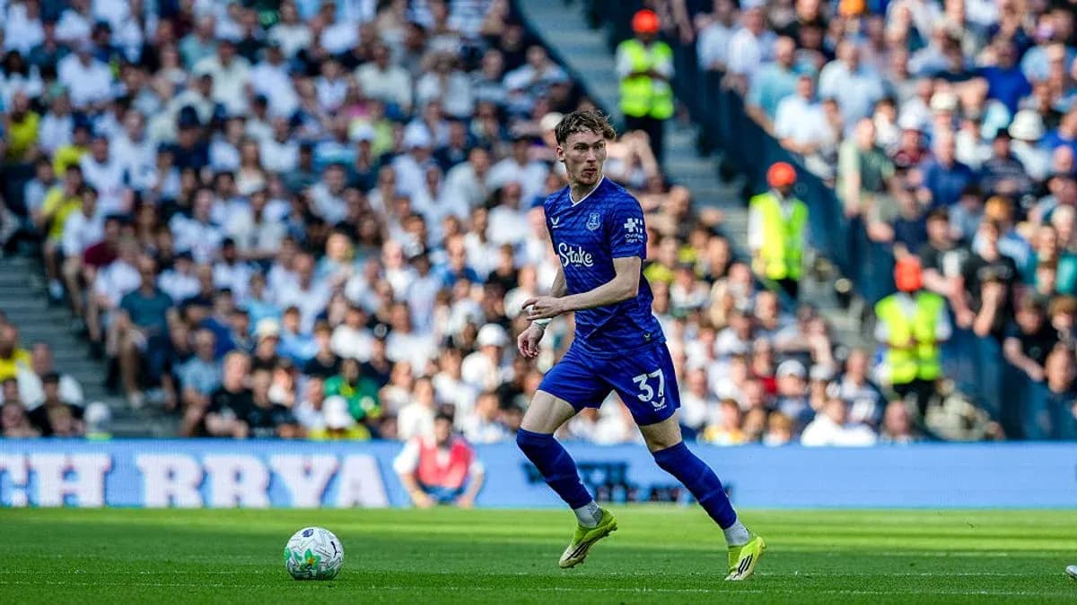 Futbolçu topu idarə edir, arxa planda azarkeşlər