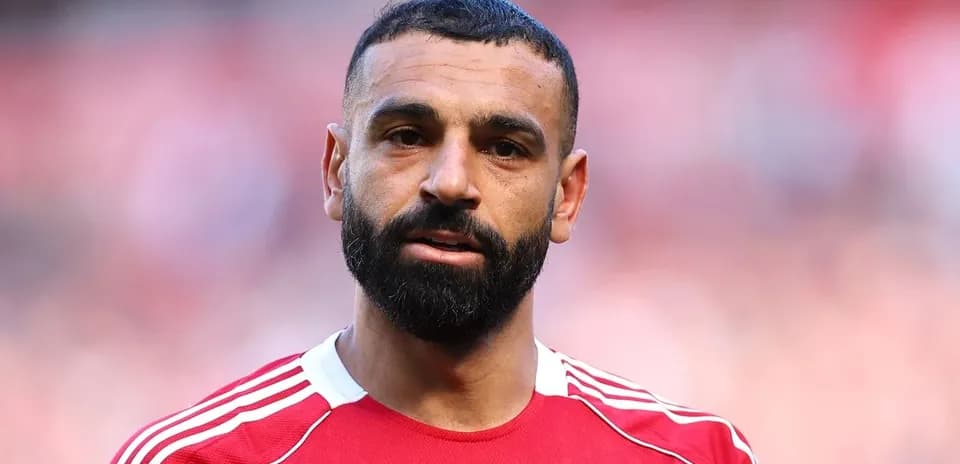 Futbolçu qırmızı formanı geyinib, meydanda durur