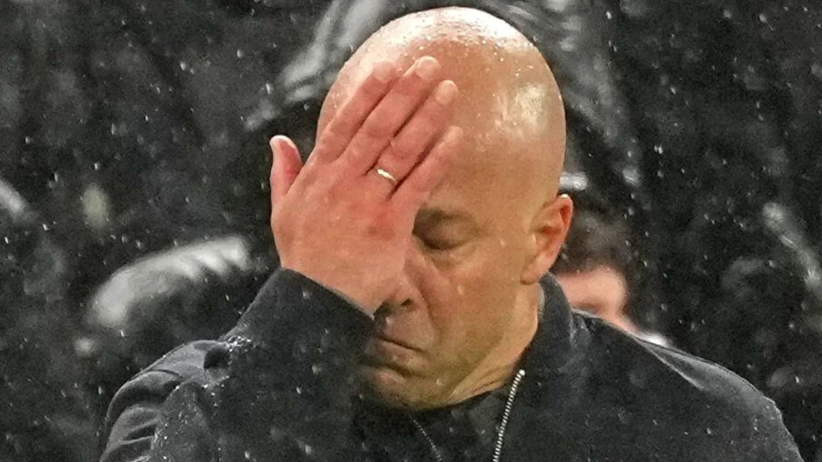 Coach with hand on face in rainy weather