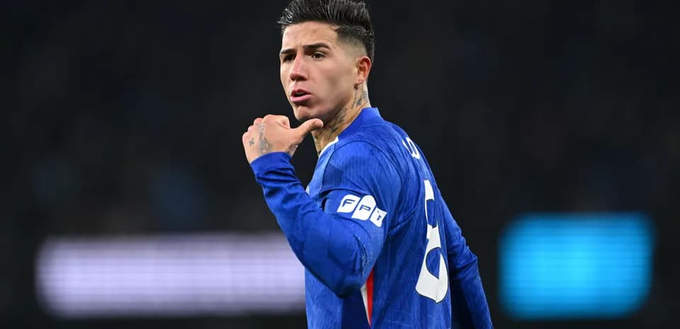 Futbolçu mavi forma ilə meydanda əlləri ilə işarə edir