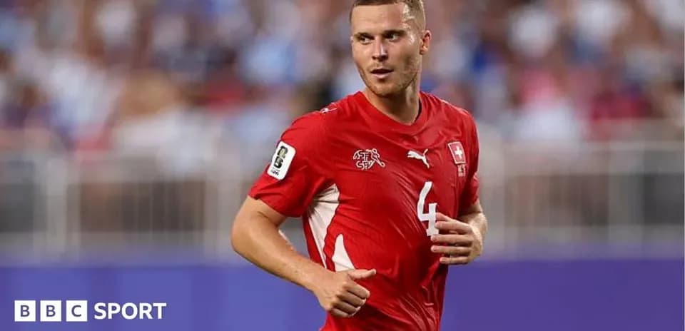 Futbolçu qırmızı forma ilə meydanda yürüyür