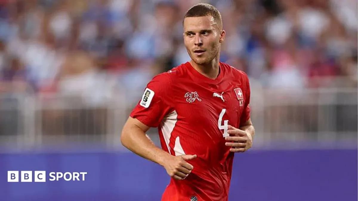 Futbolçu qırmızı forma ilə meydanda yürüyür