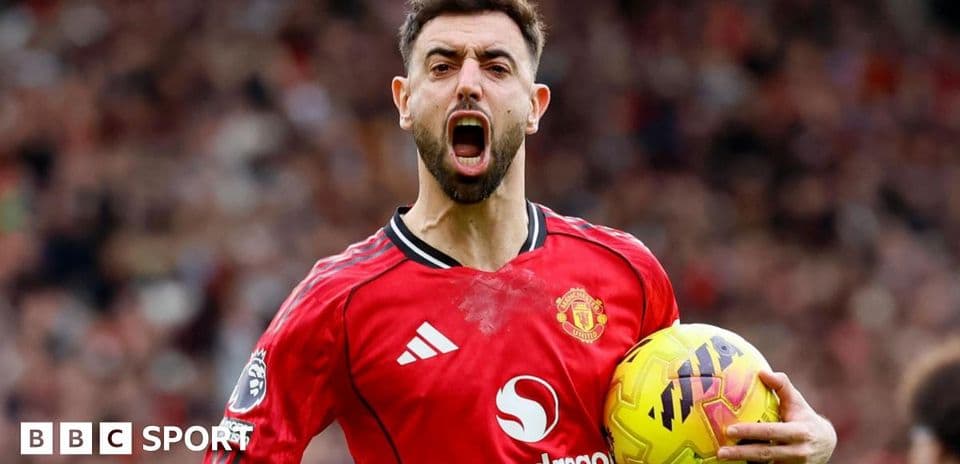 Futbolçu qırmızı forma ilə topu tutaraq sevinir